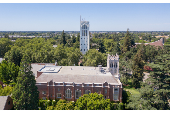 Aerial view of brick building and church nested in wooded area